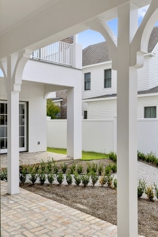 A concrete walkway nestled in between small plants leads to the covered porch.