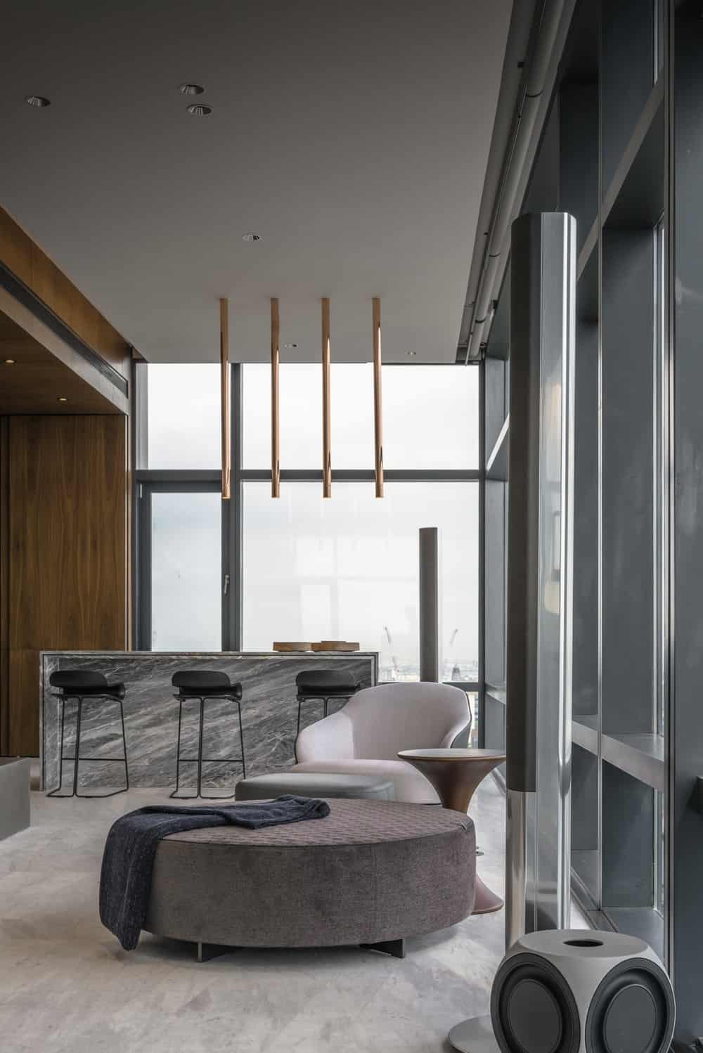 The white marble waterfall kitchen island and bar is topped with four modern pendant lights.