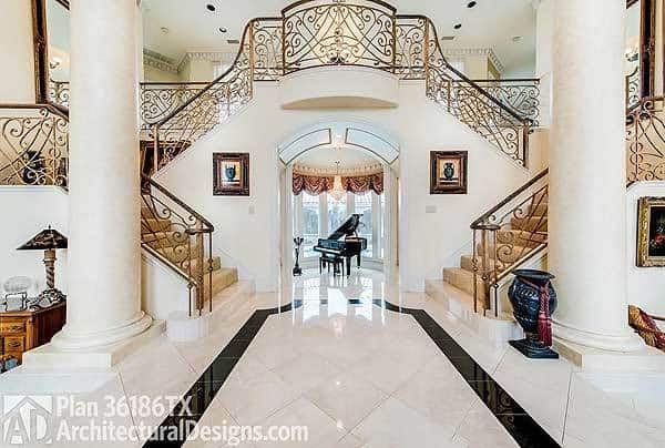 Double staircase and columns along with an open archway that leads to the music room.