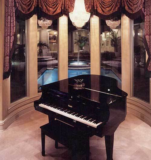 Music room with a grand piano, beaded chandelier, and a bay window overlooking the courtyard pool.