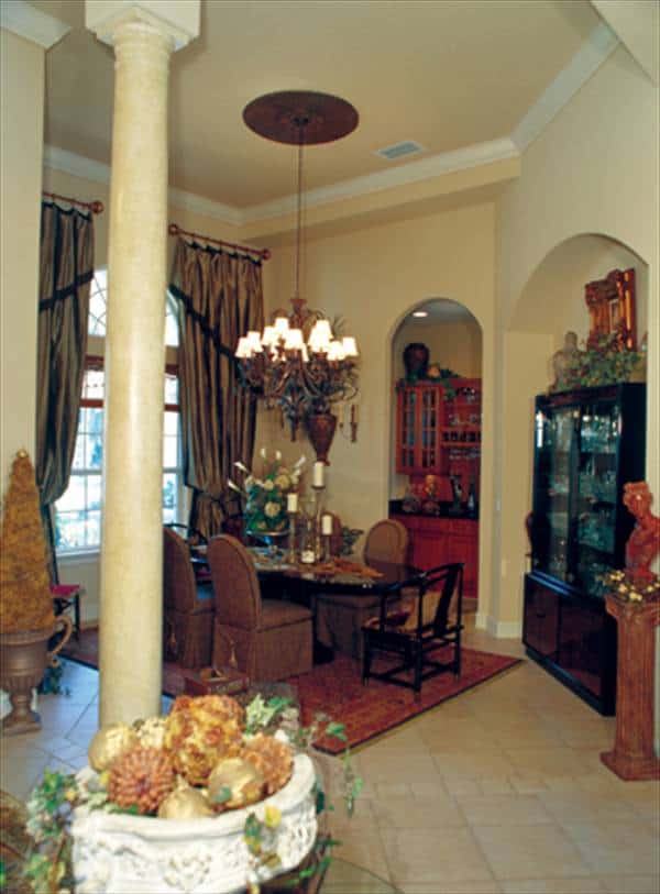 Dining room with an arched window, oval dining set, and a black display cabinet placed against the arched inset wall.