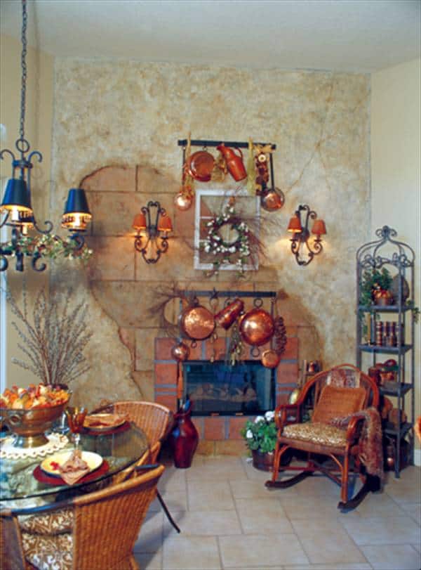 Breakfast nook with round dining set, wicker rocking chair, wrought iron shelving unit, and a glass-enclosed fireplace.