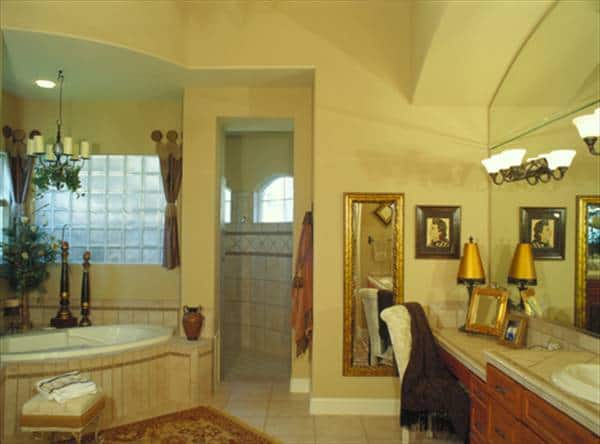 The primary bathroom has a walk-in shower, dual sink vanity, and a corner tub fixed under the glass block window.