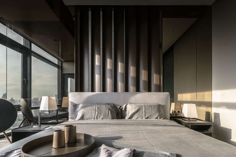 The bedroom has a gray bed with a cushioned headboard adorned by the patterned panel behind the headboard.