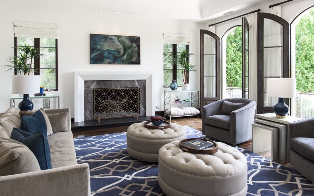 This view of the family room showcases the fireplace at the far wall with a white mantle that blends with the walls contrasted by the dark hardwood flooring. Image courtesy of Toptenrealestatedeals.com.