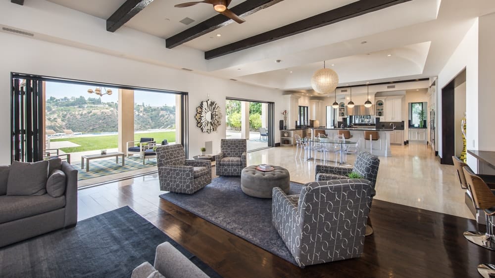 This is another view of the family room under a beamed ceiling and has large wall openings that lead to the covered patio. Image courtesy of Toptenrealestatedeals.com.