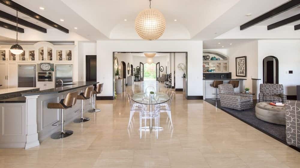 This is the spacious hallway in between the family room and the kitchen fitted with a glass table topped with a large spherical pendant light that hangs from the beige cove ceiling. Image courtesy of Toptenrealestatedeals.com.