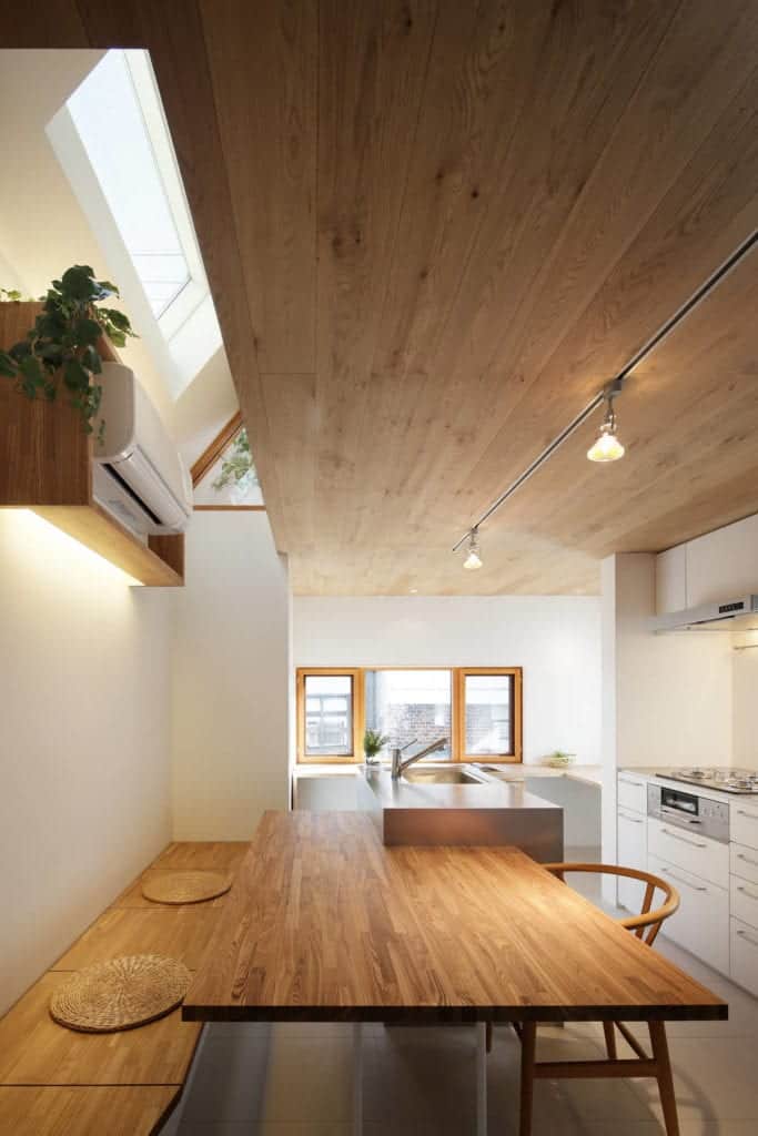 Above the built-in wooden bench of the kitchen is a floating wooden shelf that houses the split-type air conditioner.