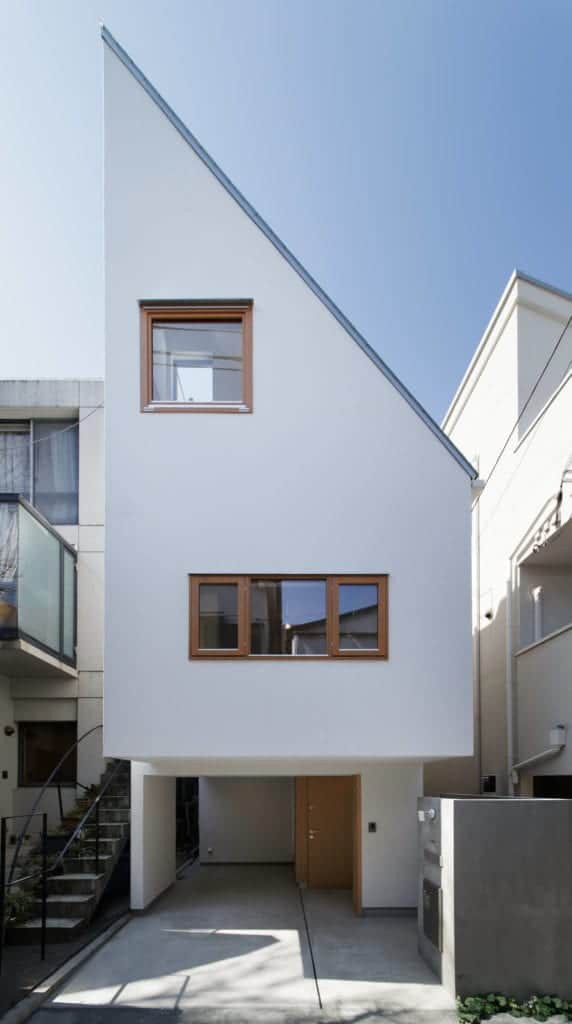 This is the front view of the bright white house showcasing its small car port underneath.