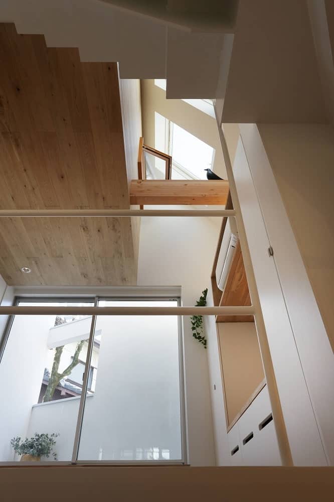 This is a look at the tall three-level ceiling of this part of the house with wooden ceilings and wooden beams adorned by a decorative figurine of a bird.