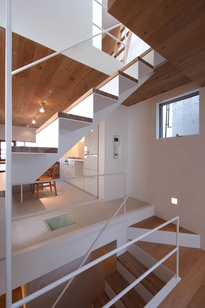 The wooden steps of the staircase match the wooden ceiling white the white walls match the white railings.