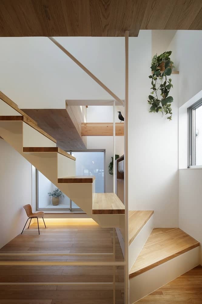 This closer look at the wooden staircase shows more of the wooden steps and bright walls adorned with hanging plants.