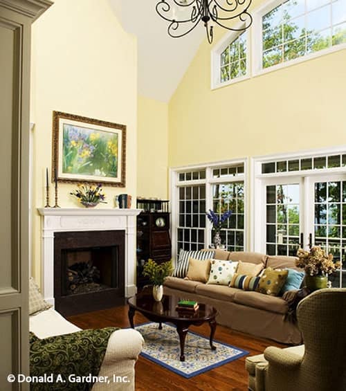 The living room has cozy fabric seats, a fireplace, clerestory windows, and a dark wood coffee table sitting on a bordered rug.