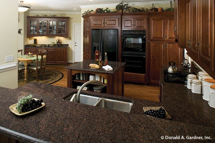 The two-tier peninsula is fitted with a double bowl sink and a gooseneck faucet.