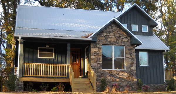 Front exterior view with stone accents and a covered porch complemented with a wooden stoop.