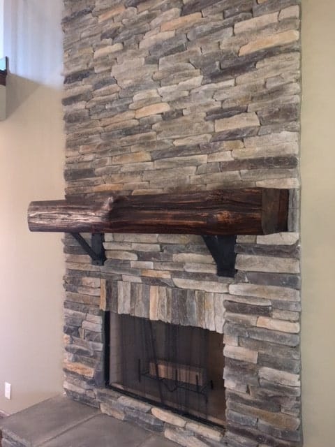 A closer look at the fireplace with stone brick surround and a wooden mantel.