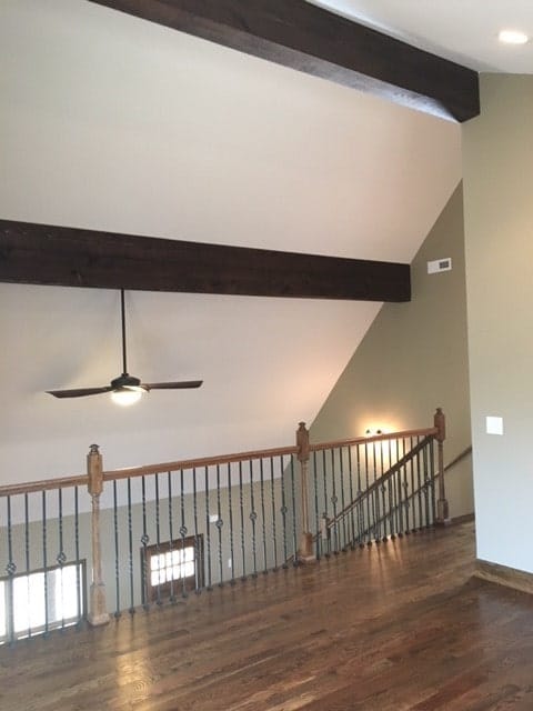 The balcony loft has ornate wrought iron railings and a vaulted ceiling lined with dark wood beams.