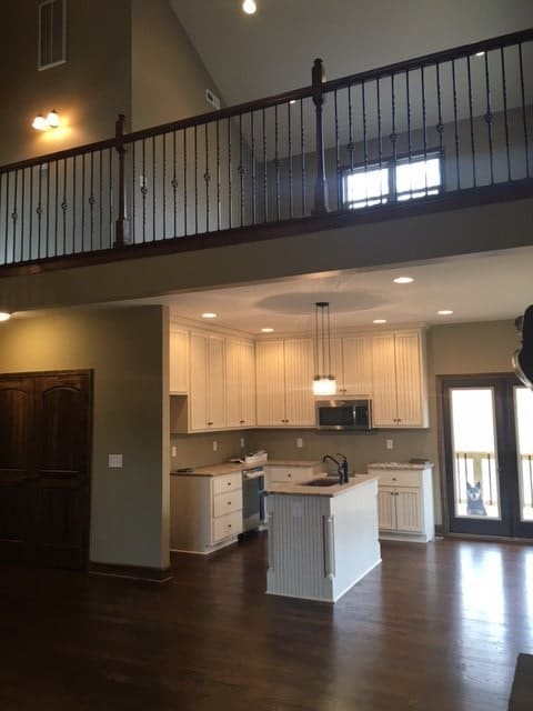 The kitchen is equipped with white cabinets, stainless steel appliances, and a prep island.