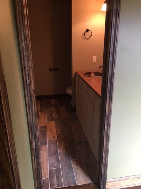 Primary bathroom with wide plank flooring, a toilet area, and dual sink vanity.