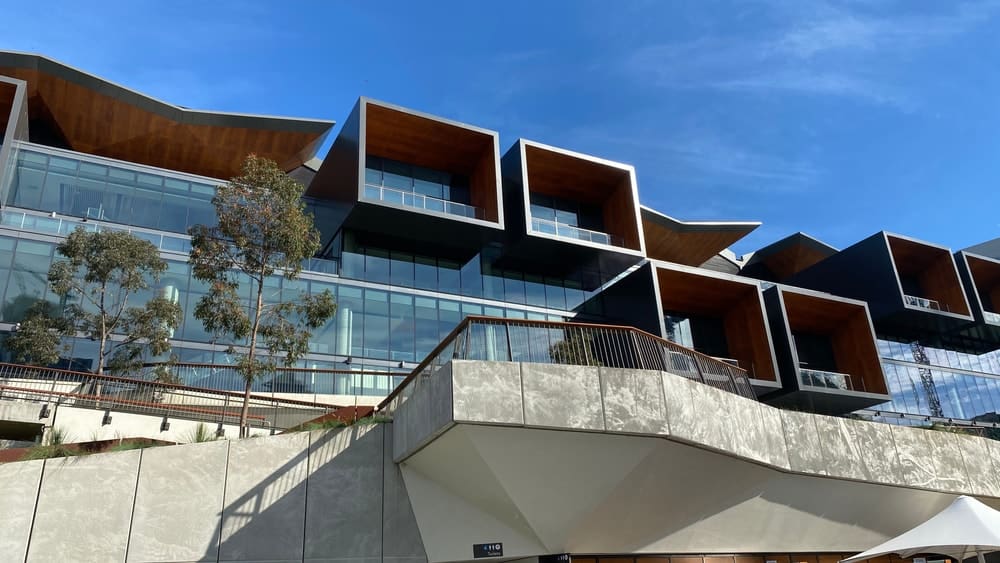 This is a close look at a modern building complex with glass walls, balconies and butterfly roofs.