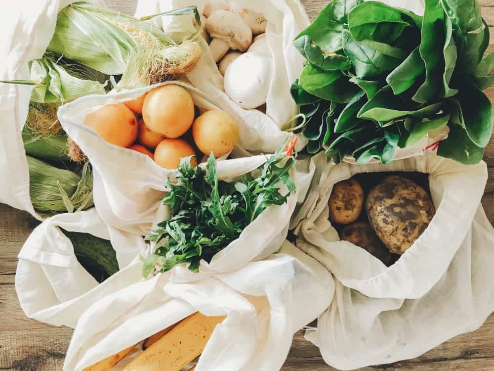 Fresh fruits and vegetables in eco-friendly reusable bags.