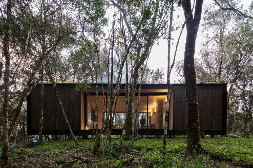 This is a look at the house that has dark exteriors complemented by the large glass walls that also give a peek of the interiors.