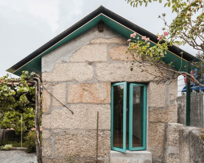 This is a small home with rustic and textured stone walls complemented by the colorful exterior accents and landscaping.