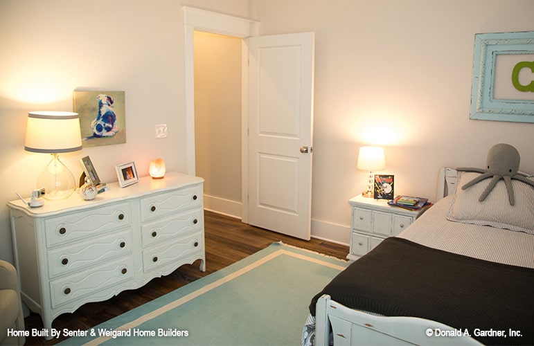 Another bedroom with white furnishings, hardwood flooring, and cream walls adorned by lovely artworks.