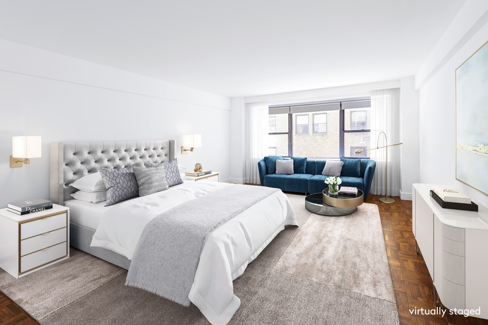 This is the primary bedroom that has a large gray tufted bed that pairs well with the area rug and the bright white walls. Image courtesy of Toptenrealestatedeals.com.