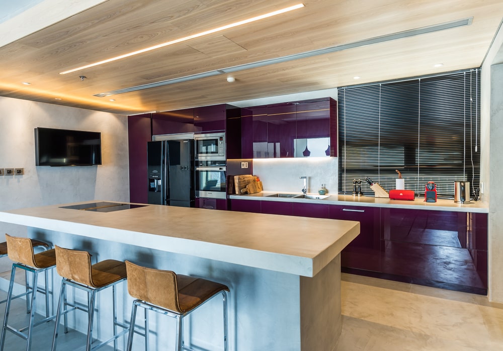 This purple wall matches well with the purple cabinetry of the kitchen across from the island.