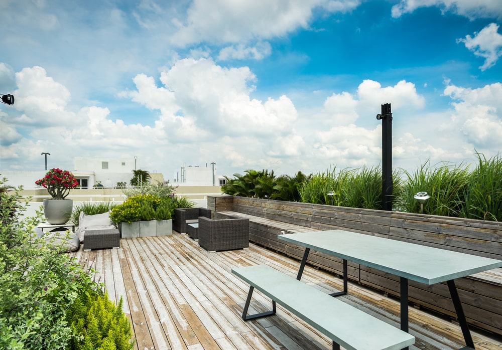 The large area is also fitted with an outdoor dining set adorned witha row of planters behind the built-in bench.