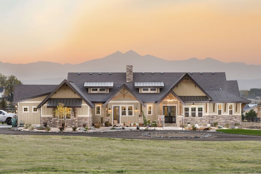 Front exterior view showing the stone accents, shed dormers, and multiple gables adorned with decorative wooden trims.