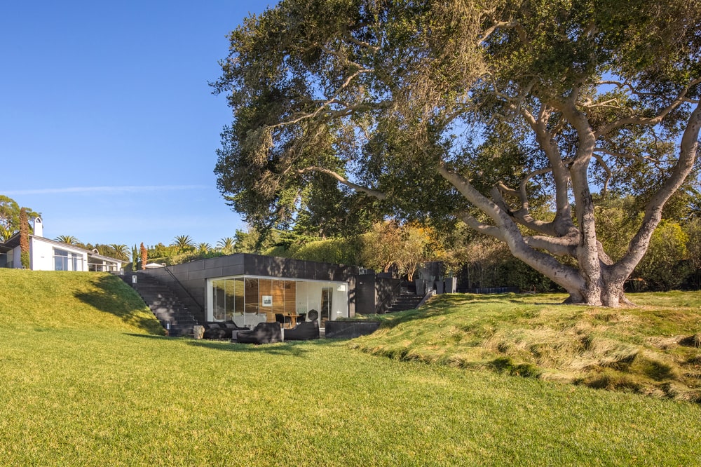 This is a daytime view of the guest house shaded by a large tree and complemented by the large grass lawn. Image courtesy of Toptenrealestatedeals.com.