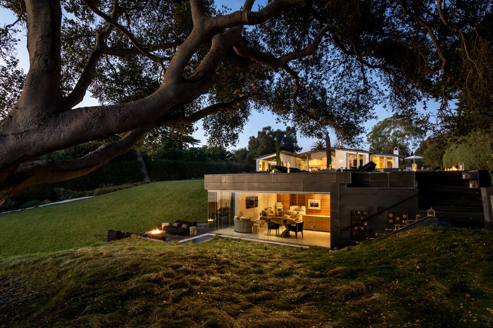 This is a nighttime view of the guest house with a warm glow to its open walls and windows showcasing the interiors. Image courtesy of Toptenrealestatedeals.com.