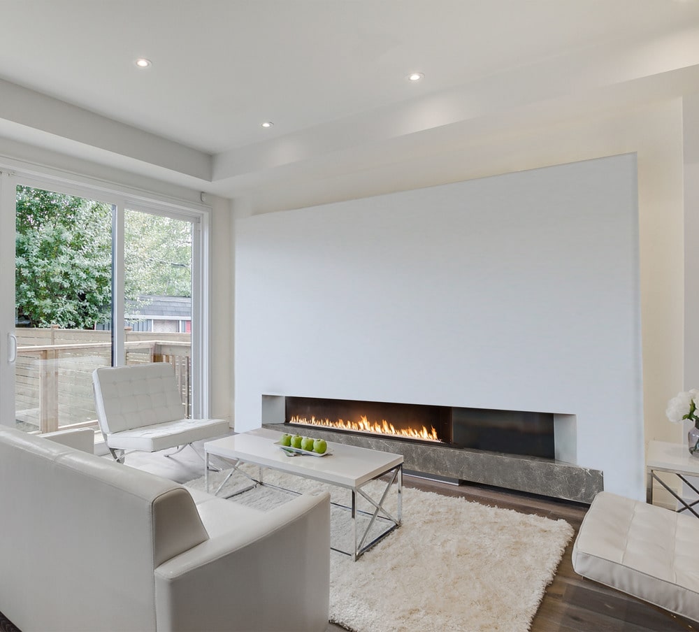 This is the family room with a beige sofa set warmed by the modern fireplace on the other side of the rectangular modern coffee table.