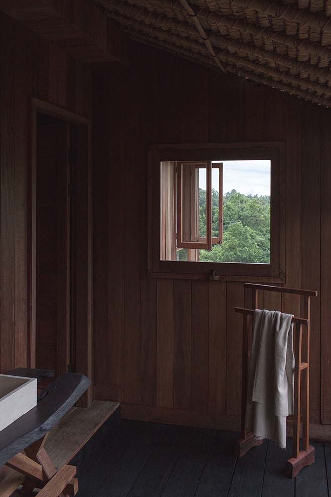 This is a close look at the bathroom with a small window, a beamed shed ceiling and a rustic floating sink.