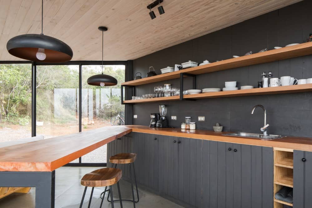 This is a close look at the kitchen with wooden butcher block counters that match the shelves contrasted by the black walls and black cabinetry.