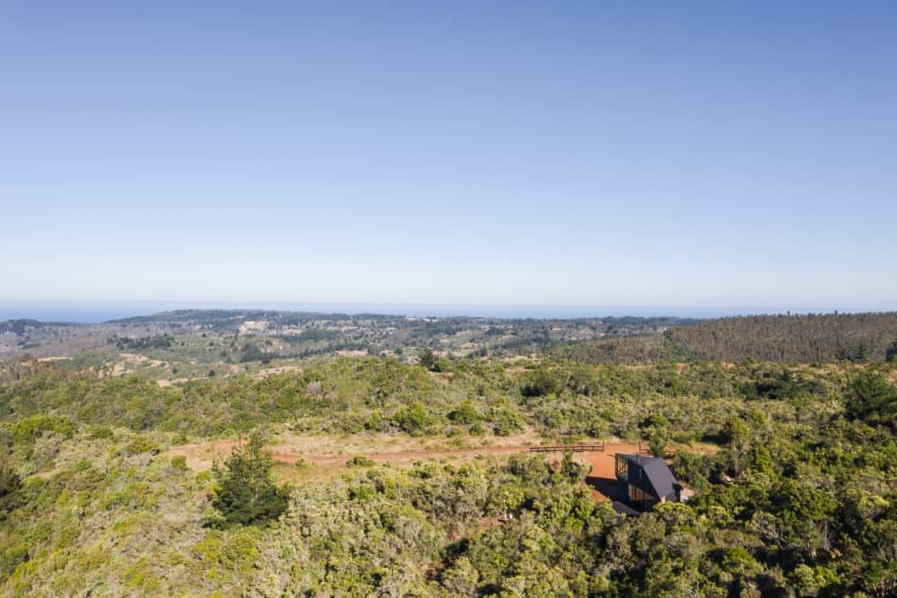 This is an aerial view of the house showcasing the isolation and the surrounding landscape of trees.