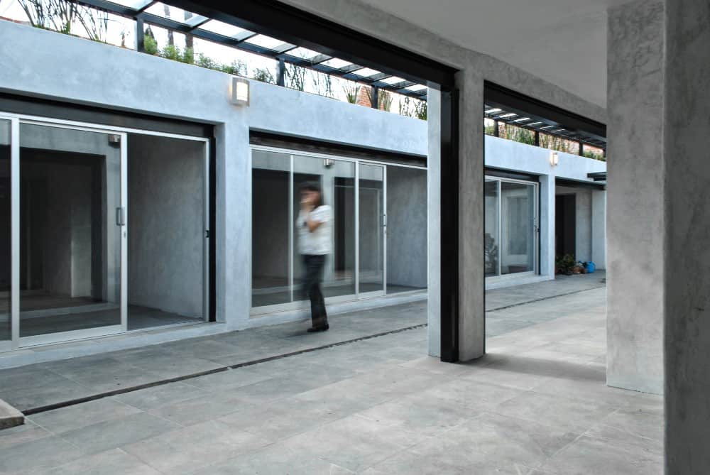 On the other side of the glass sliding doors is a large open covered area with concrete columns and concrete flooring.