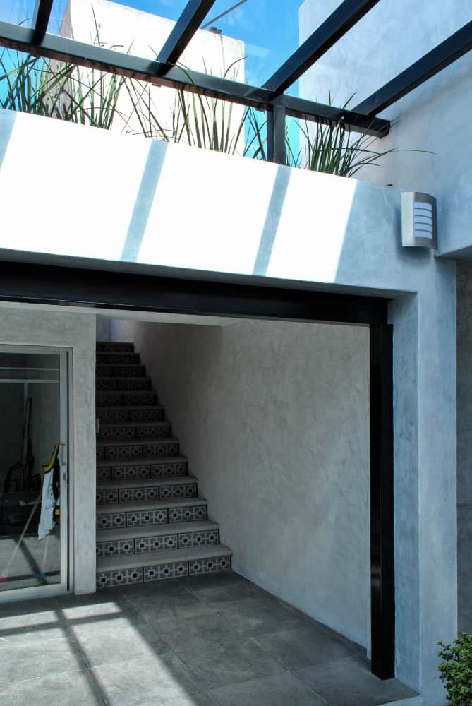 On the side of the glass doors is a set of steps with patterned tiles and concrete steps leading to the upper level.