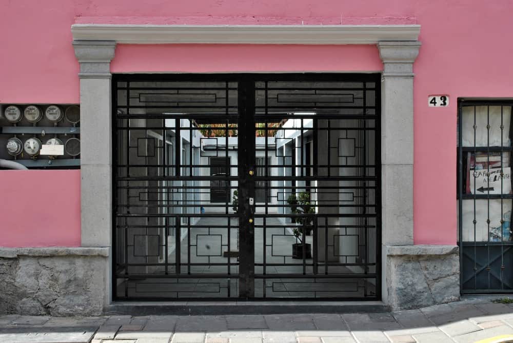 This is an exterior view of the house showcasing the outer gate with dark wrought-iron structures that has intricate details.