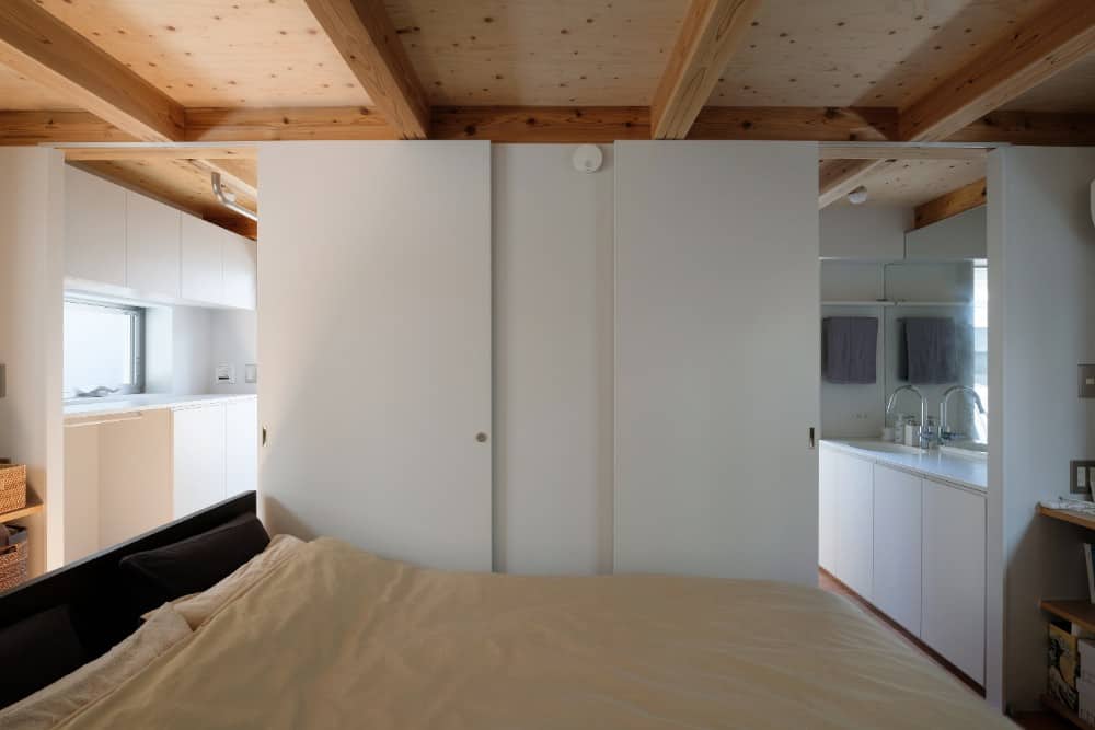 This is another look at the bedroom with its black bedframe and white walls that slide open to reveal other areas of the house.