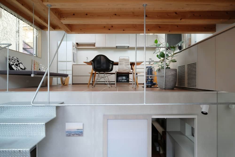 This is a view of the dining area and kitchen area from the vantage of the lower level with a set of metal stairs leading up to the dining area.