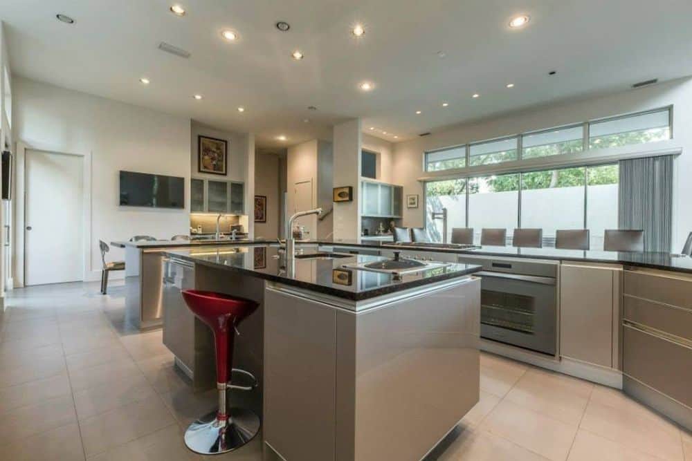 The kitchen offers taupe cabinets and a multi-use island paired with a red bar stool.