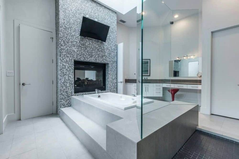 Primary bathroom with a deep soaking tub warmed by a double-sided fireplace.