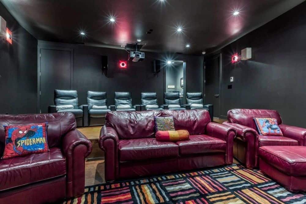 Media room with black walls, leather seats, and a patterned area rug.