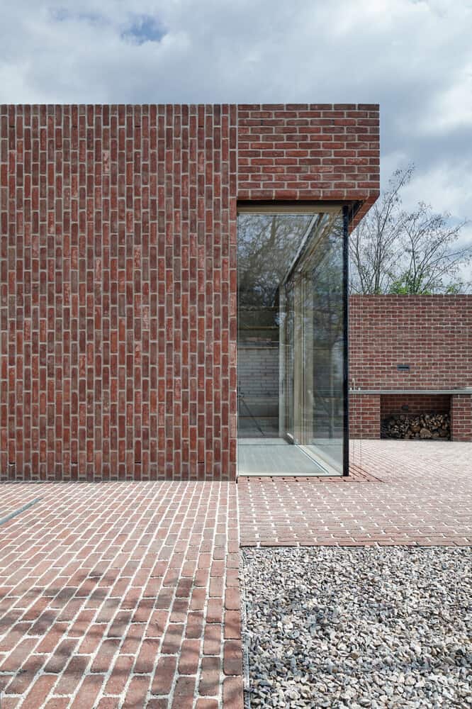 This is a corner of the house with corner glass walls that contrast with the red brick exterior walls.