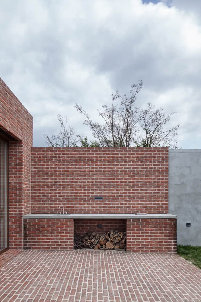 This is an outdoor kitchen with a red brick structure and a large concrete counter.