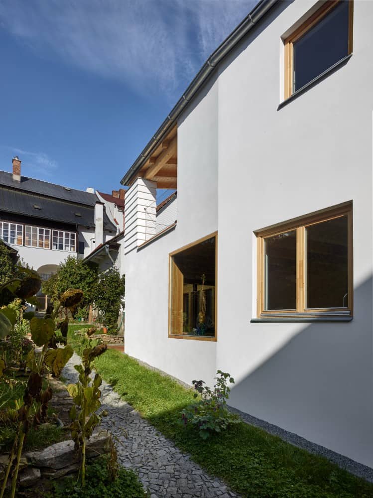 Exterior shot showing the white painted wall and windows with brown frames.