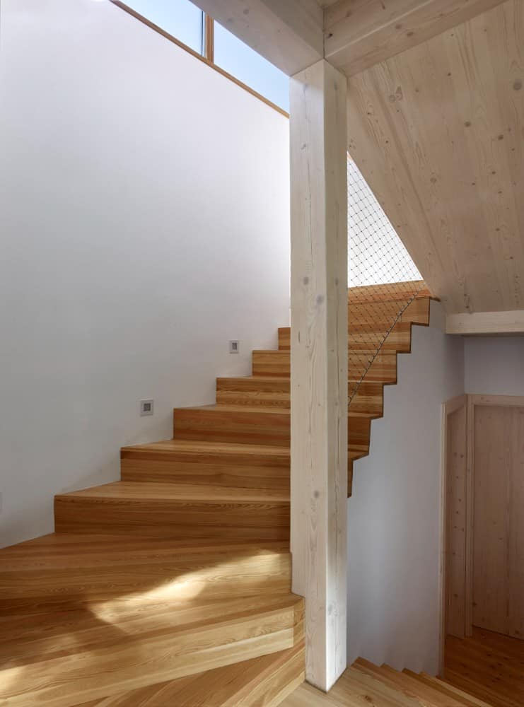 Daylight photo of wooden staircase and white painted wall.